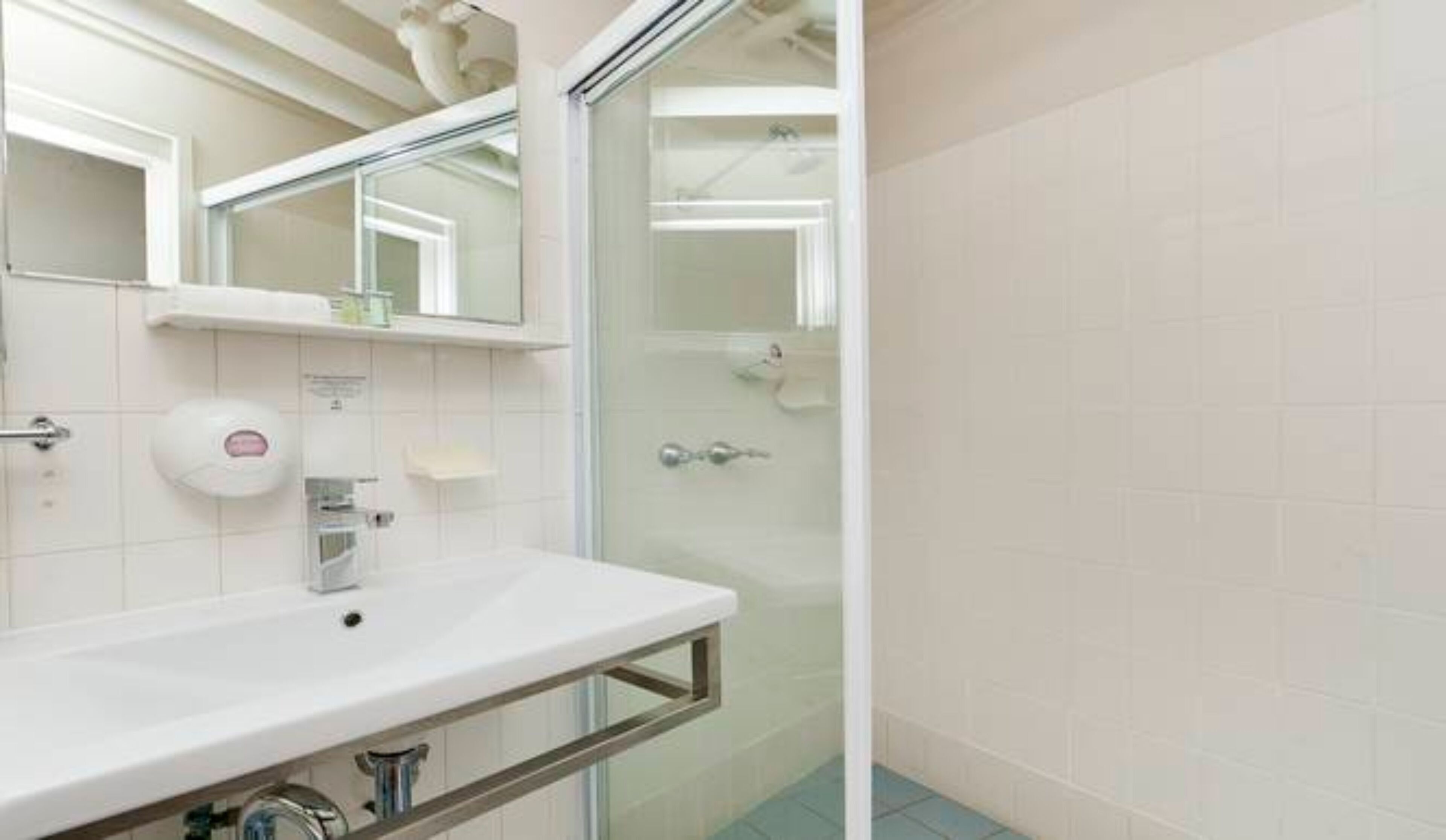 A bathroom with a white sink, a mirror, and a glass shower enclosure.