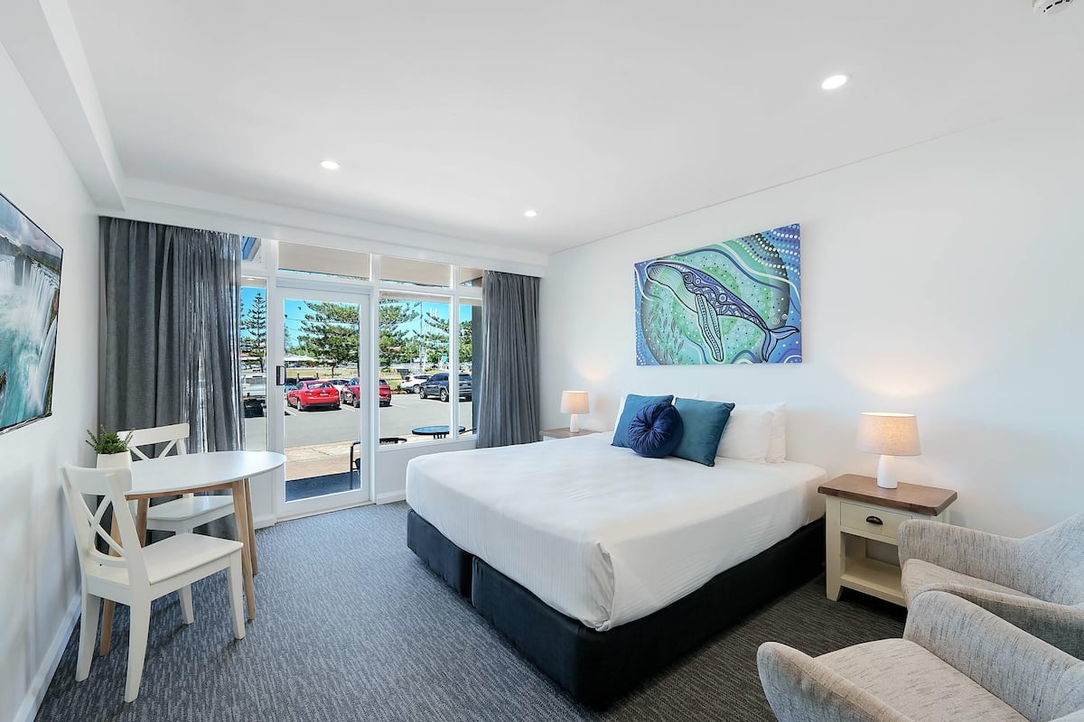 A hotel room with a bed, bedside tables, a desk, and a chair.