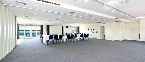 A conference room with a long table, chairs, and a large screen.