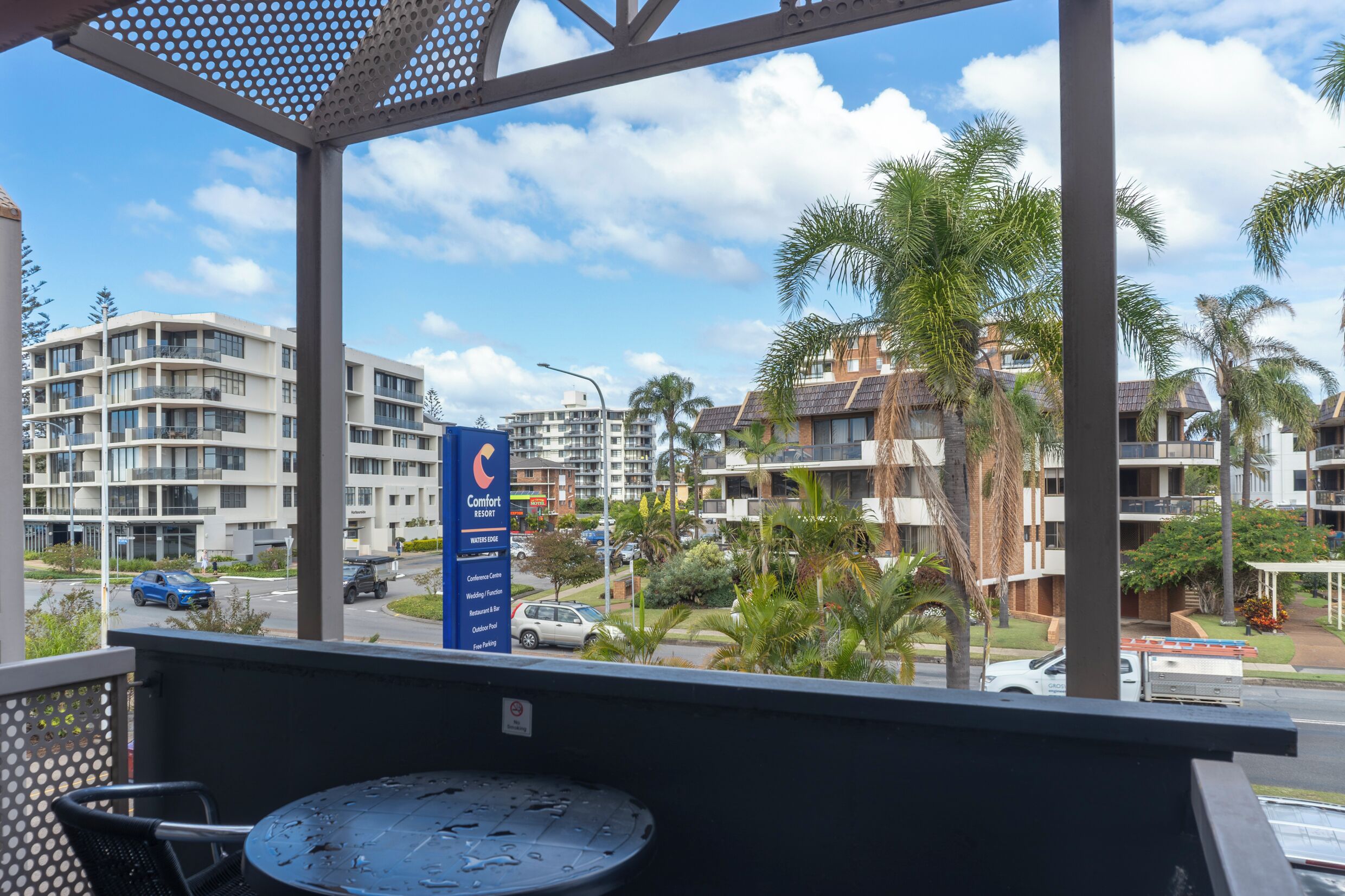 A balcony with a view of a hotel complex, including multiple buildings and palm trees.