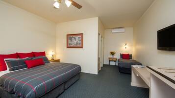 A hotel room with a large bed, a smaller bed, a desk, and a ceiling fan.