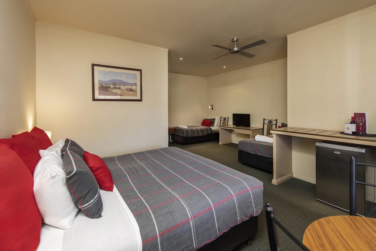 A hotel room with a bed, desk, television, and a refrigerator.