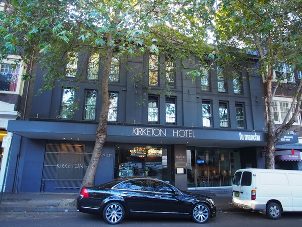 A building with a sign reading "KIRKETON HOTEL" and a parked black car in front.