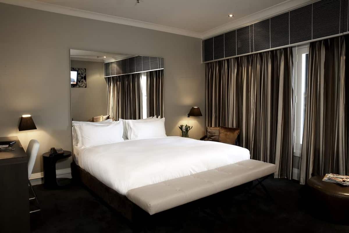 Habitación de hotel con una cama grande, lámparas de noche, un escritorio y una silla.