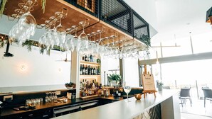A bar area with a long counter, wine glasses hanging above, and a variety of bottles on shelves. - Mercure Charlestown (Adamstown Heights)