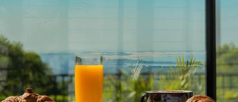 A breakfast setting with croissants, a glass of orange juice, and a cup of coffee on a table with a scenic view.
