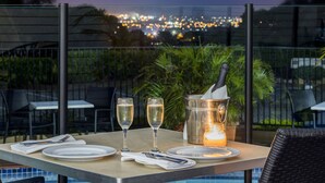 A table set for two with a bottle of champagne, two glasses, and a candle. - Mercure Charlestown (Adamstown Heights)