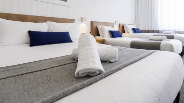 A hotel room with three beds, white bedding, and a large window with curtains. - Mercure Charlestown (Adamstown Heights)