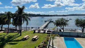 A pool area with a view of the water and boats, palm trees, and a dock.
