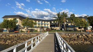 A wooden boardwalk leading to a building with balconies and a pool area.