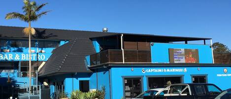 A blue building with a sign reading "BAR & BISTRO" and "CAPTAINS @ MARINERS".