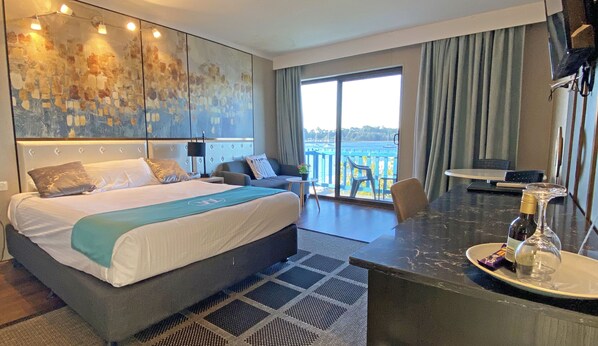 Relax in a stylish room with a large bed, seating area, and ocean views through a large window.