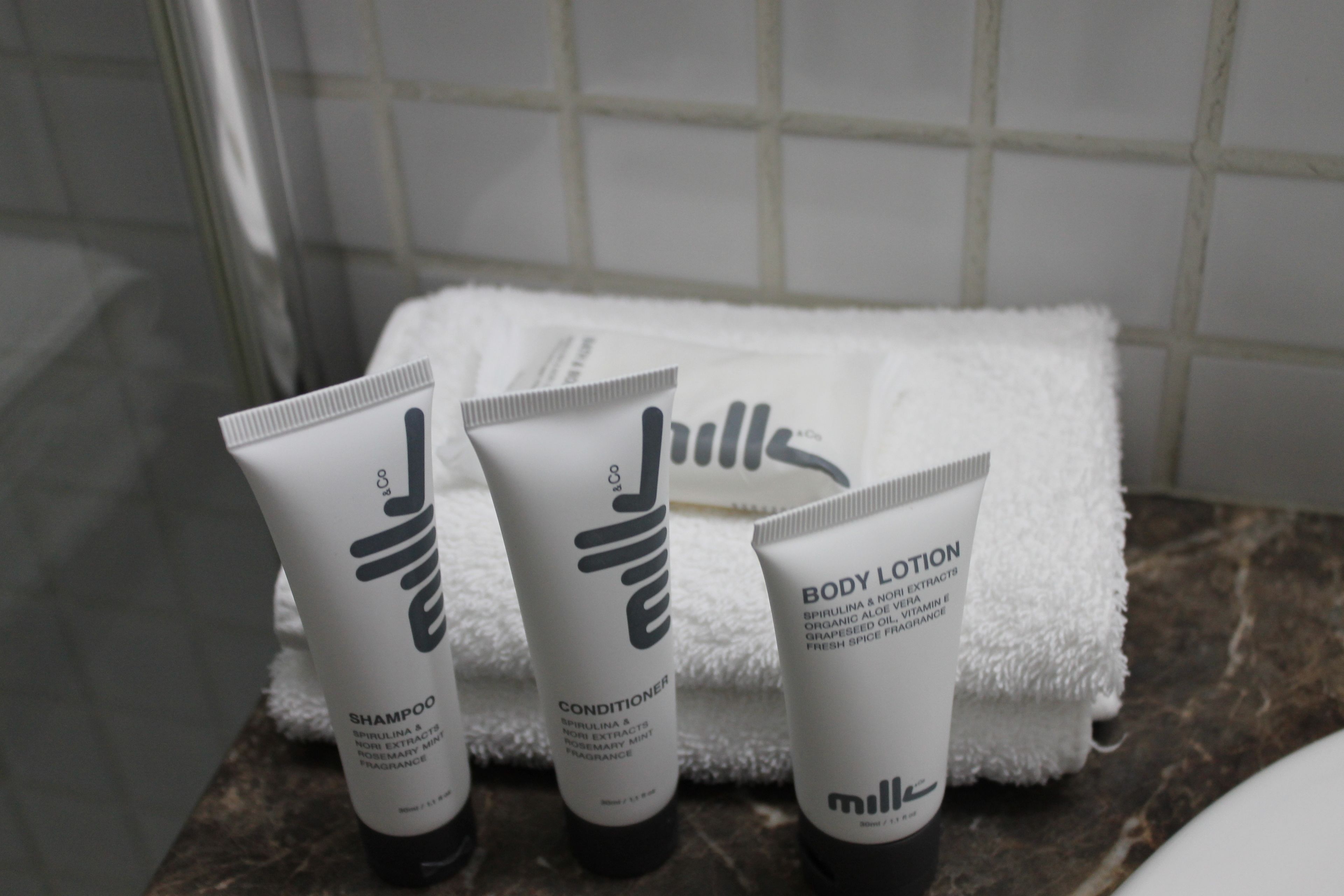 Three bottles of body lotion, shampoo, and conditioner on a bathroom counter.