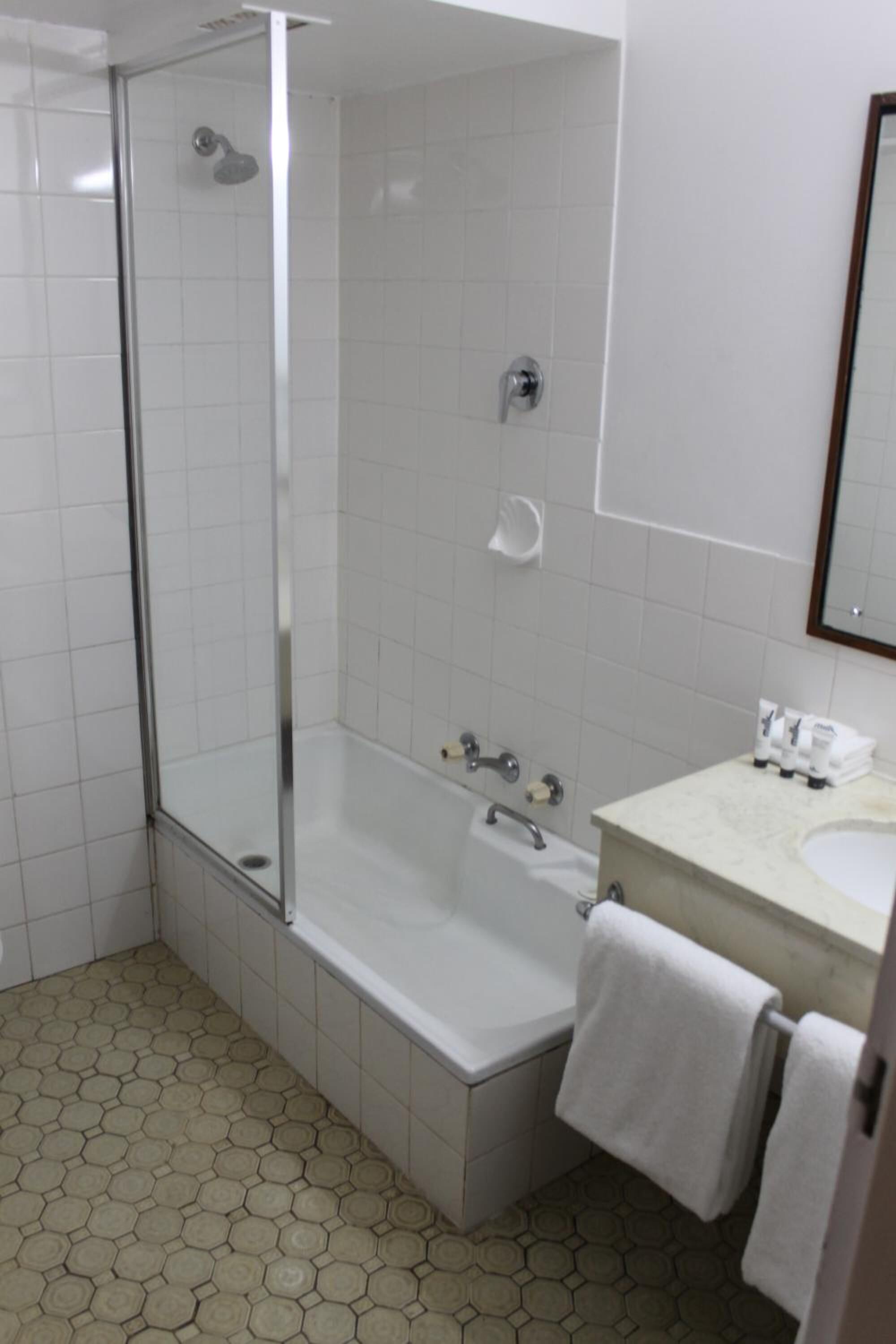 Un baño con cabina de ducha de vidrio, una bañera y un lavabo con espejo.