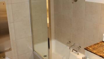 A modern bathroom with a glass-enclosed shower, a white bathtub, and a marble countertop.