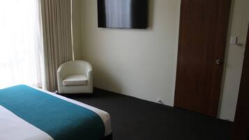 Una habitación de hotel con una cama, una silla, un televisor y una puerta.