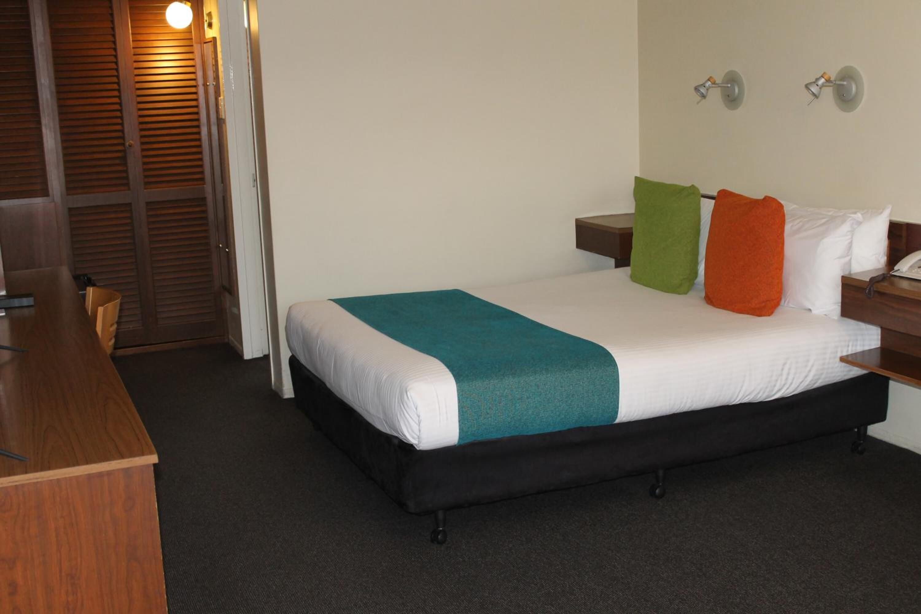 Una habitación de hotel con cama, escritorio y armario.
