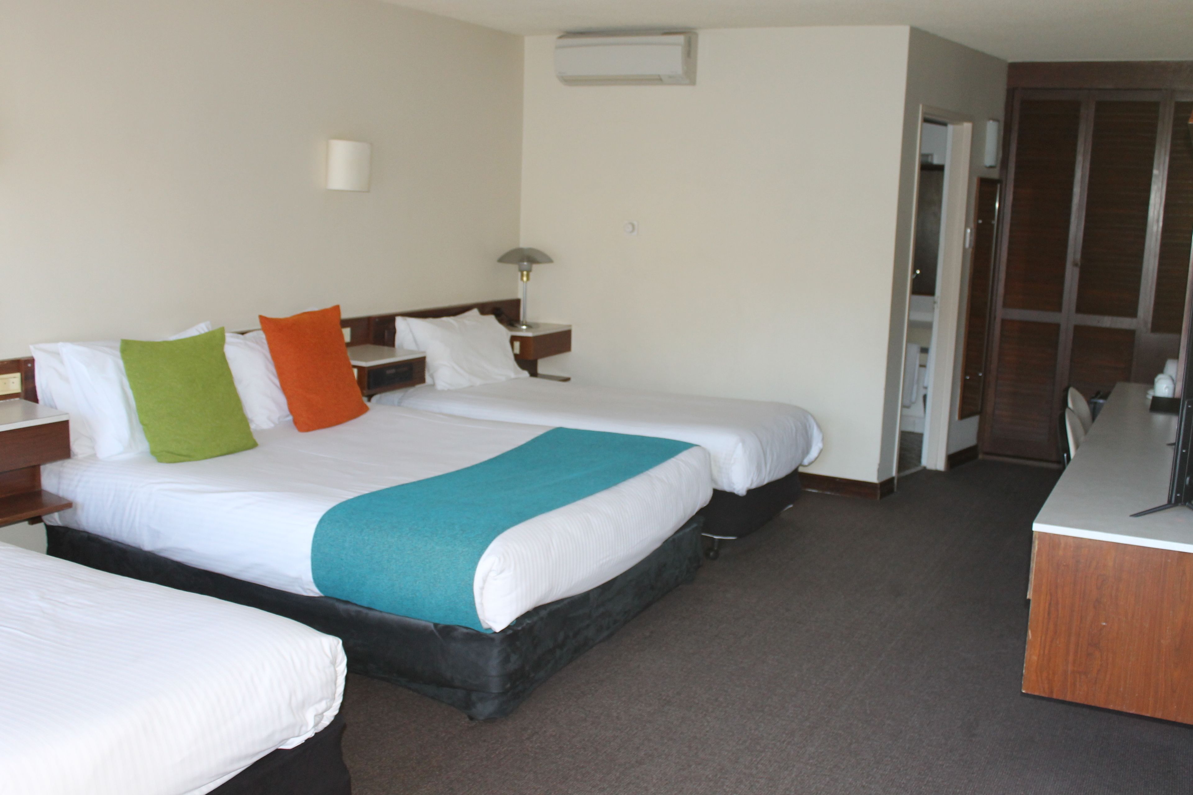 Habitación de hotel con dos camas, un escritorio y un armario.