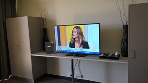Un televisor sobre un mueble mostrando un programa de noticias.
