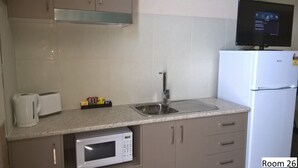 Una cocina con microondas, tostadora, lavamanos y refrigerador.