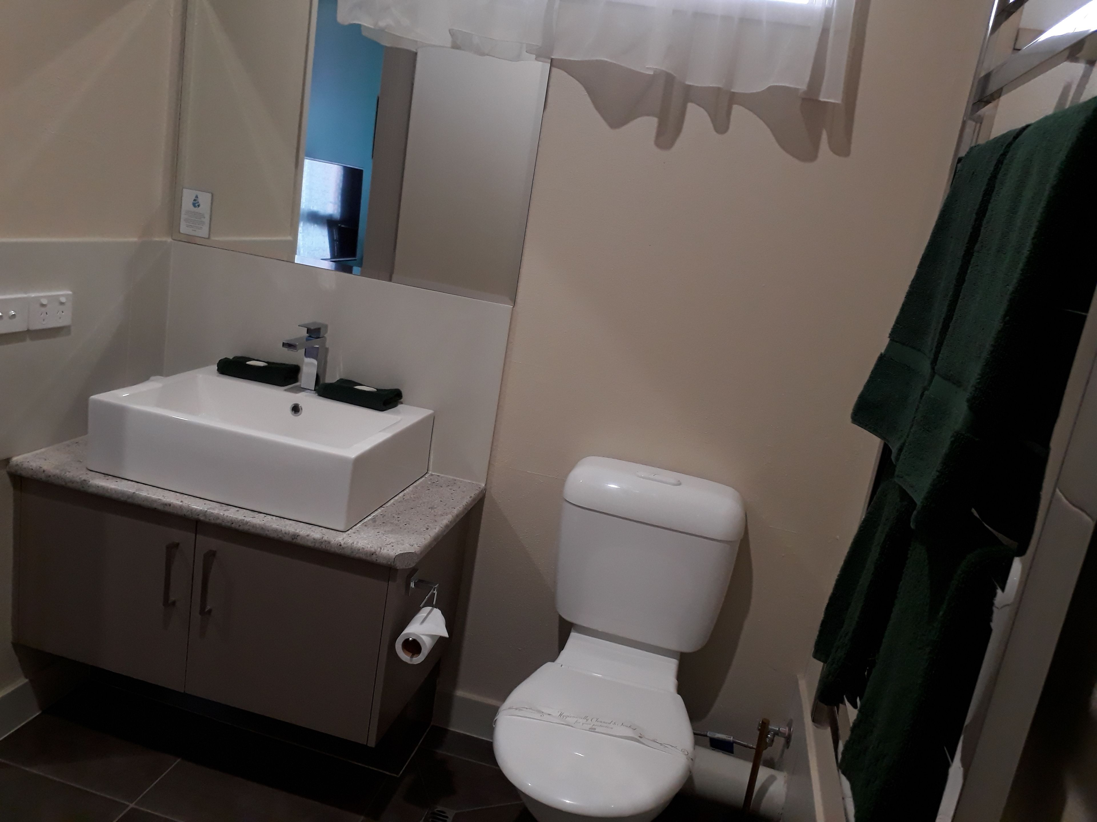 Un baño con lavamanos, inodoro y espejo blancos.