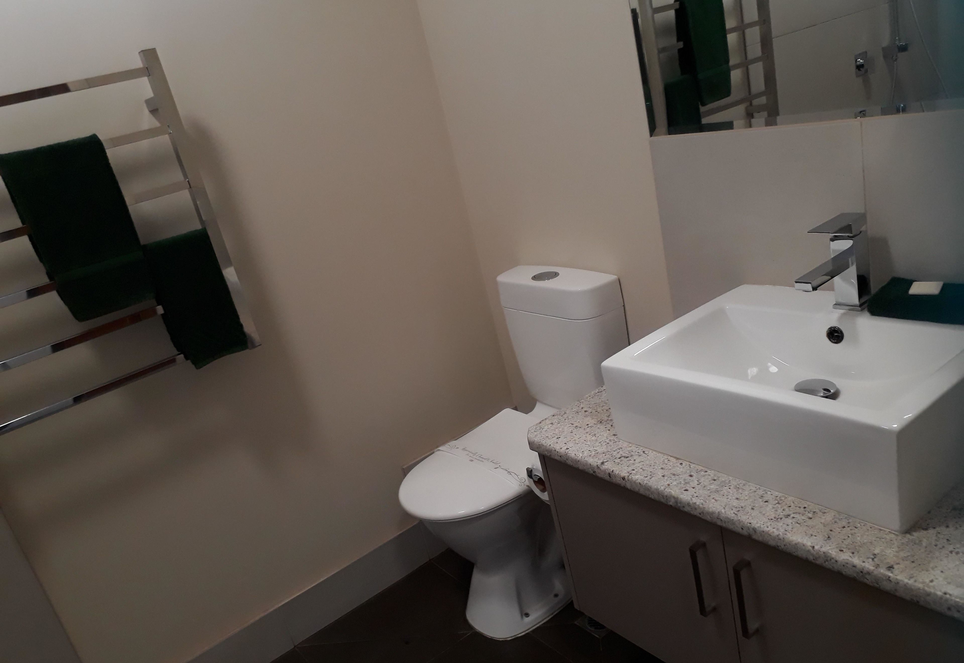 Un baño con inodoro blanco, lavamanos y un perchero para toallas.