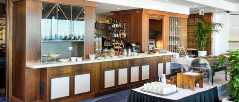 A hotel bar with wooden cabinetry, a coffee station, and a buffet setup.