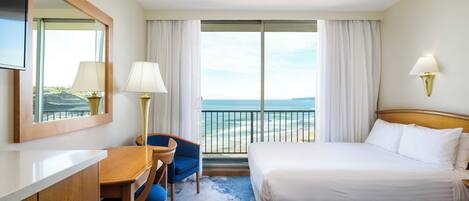 A hotel room with a bed, a desk, a chair, a TV, and a view of the ocean.
