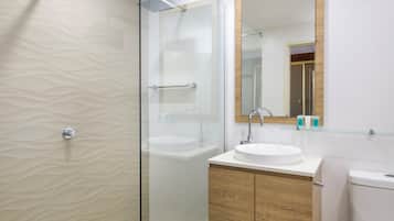 A modern bathroom with a glass shower enclosure, a white sink, and a wooden vanity.