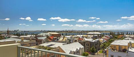 A residential area with various buildings, a clear blue sky, and a body of water in the distance.