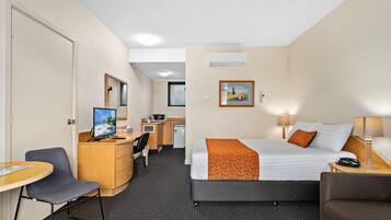 Een hotelkamer met een bed, bureau, stoel en een kleine kitchenette.
