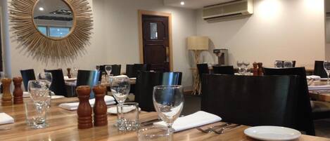 A dining area with tables set for service, numbered placemats, and a decorative mirror on the wall.