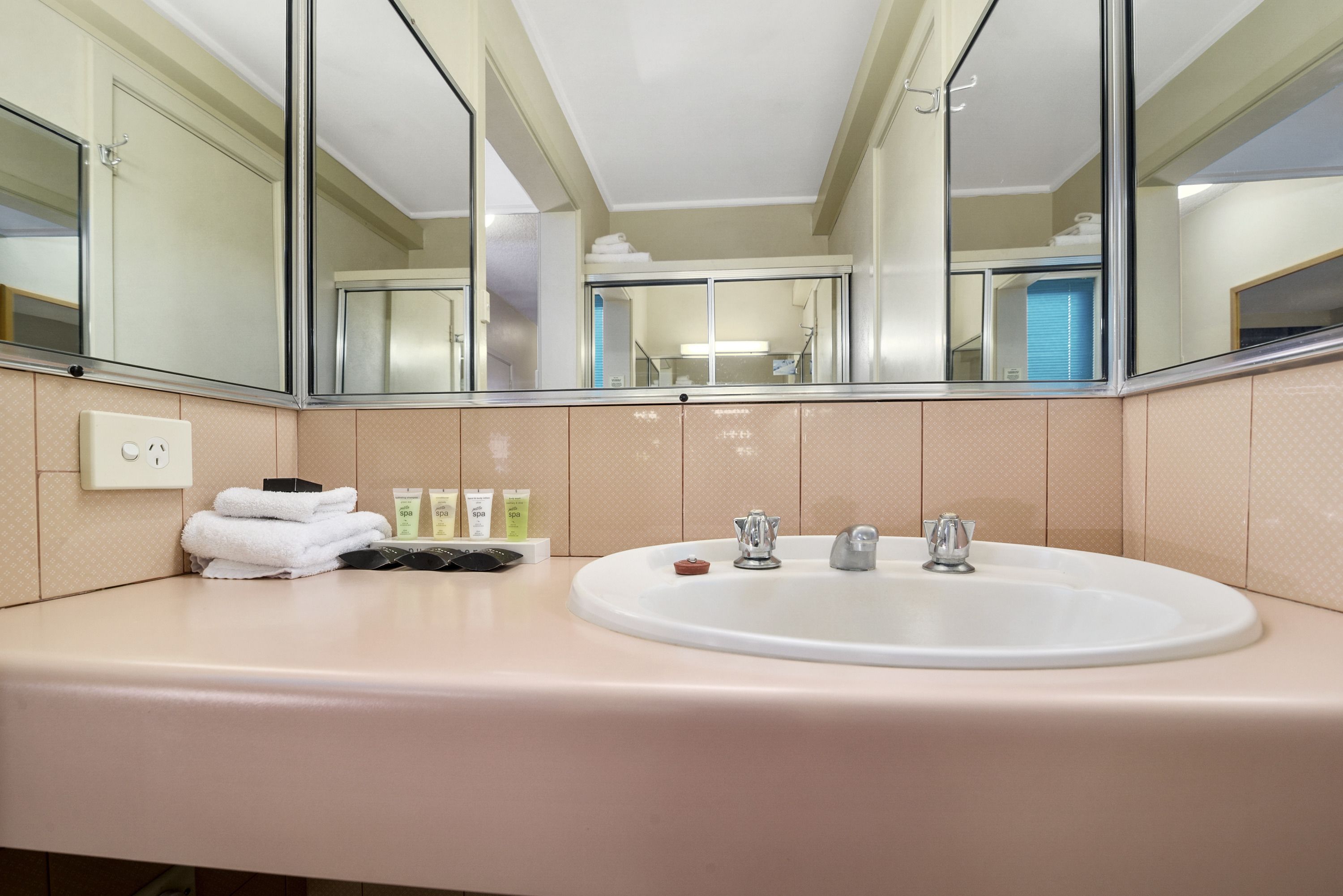A bathroom with a large mirror, a sink, and toiletries.