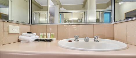 A bathroom with a large mirror, a sink, and toiletries.