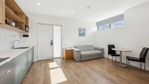 Eine moderne Küche mit Holzböden, einem grauen Sofa und einem Esstisch mit Stühlen.