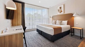 Ein modernes Hotelzimmer mit Bett, Schreibtisch und Stuhl.