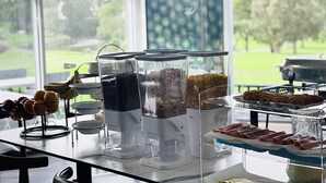 Un buffet de petit-déjeuner comprenant du café, des céréales et des viennoiseries.