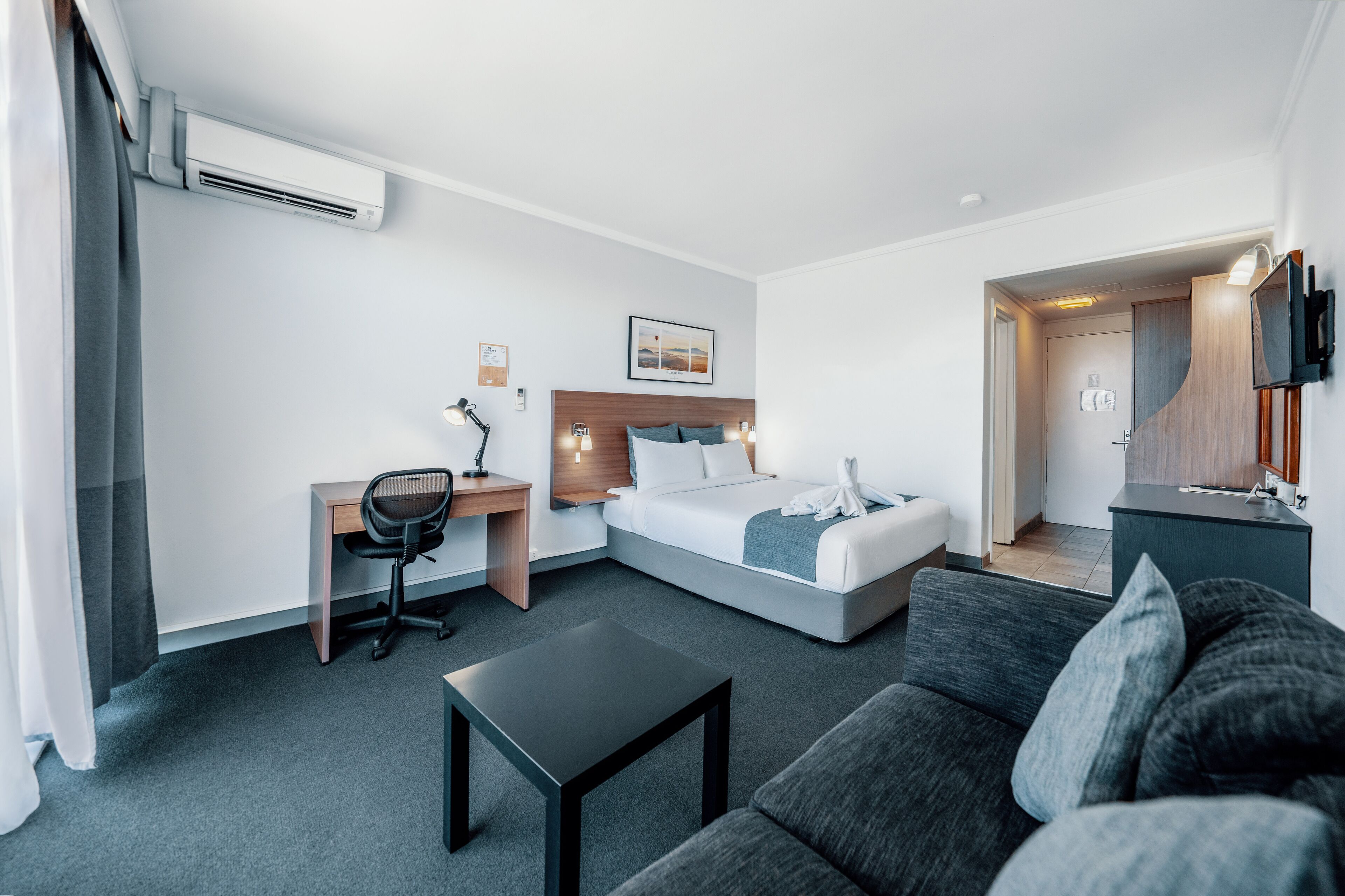 Una habitación de hotel moderna con cama, escritorio y sofá.
