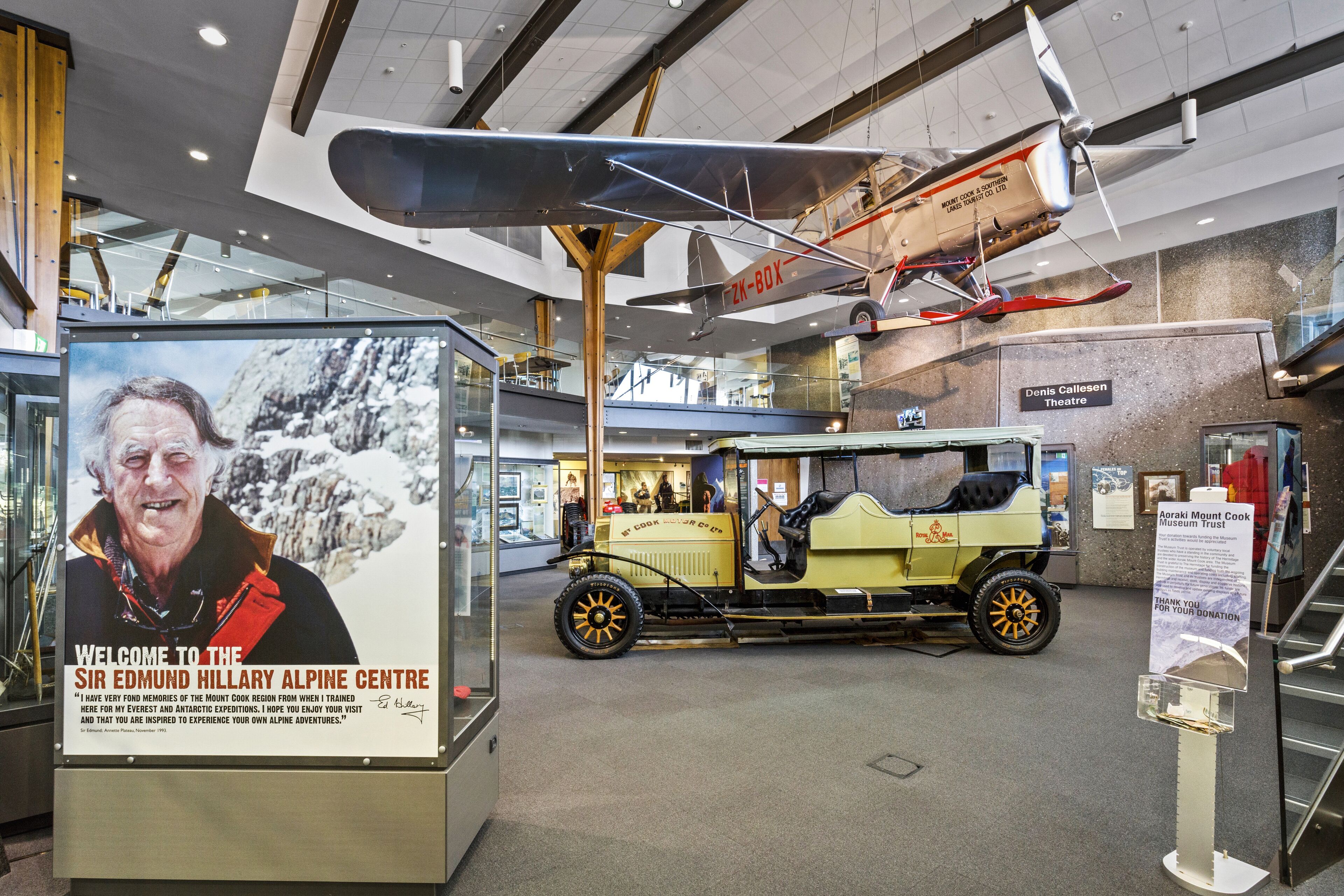 A museum exhibit with a vintage car and a hanging airplane model.