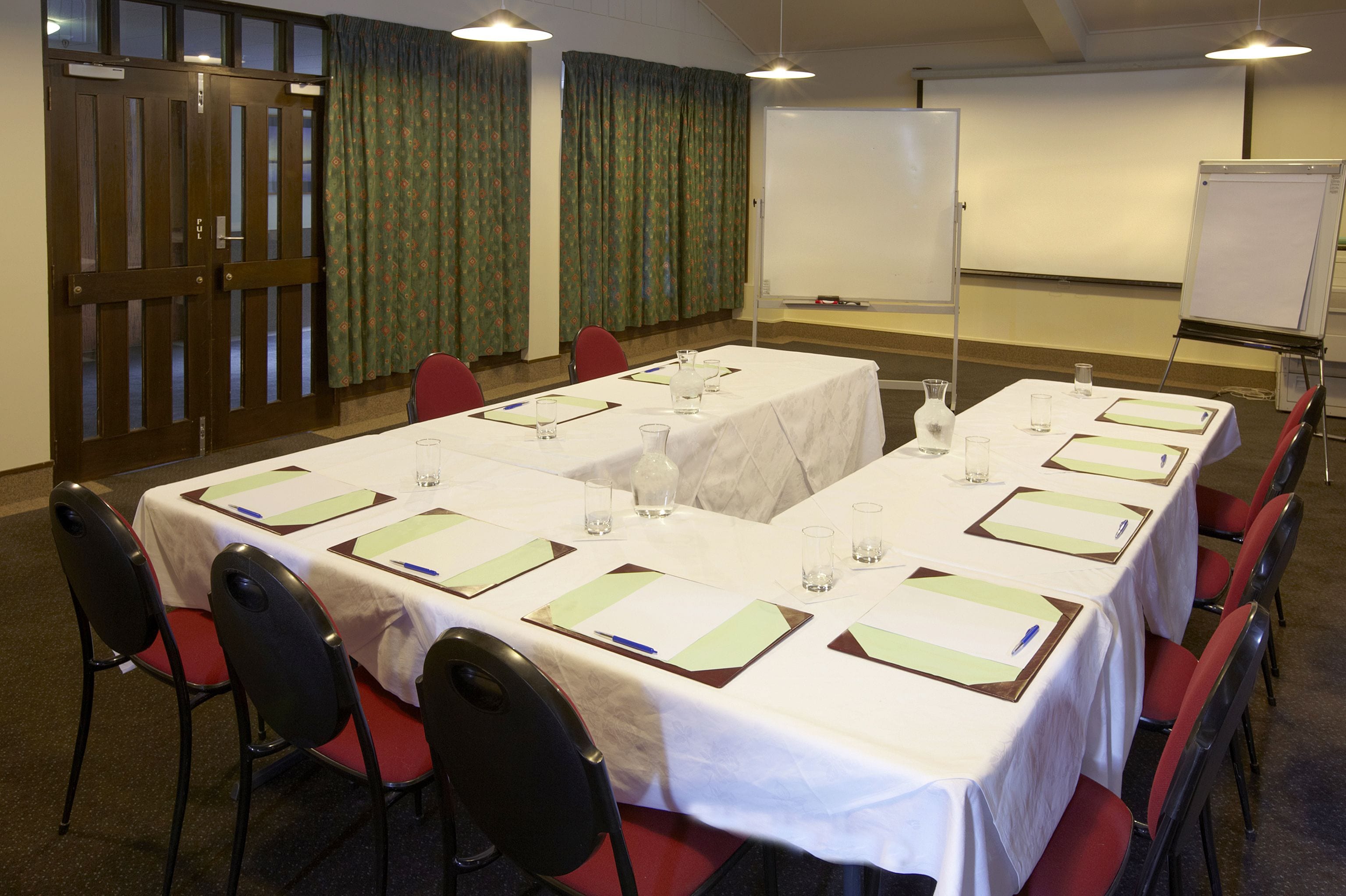 A conference room with a long table set for meetings, equipped with chairs, water glasses, and nameplates.