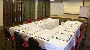 A conference room with a long table set for meetings, equipped with chairs, water glasses, and nameplates.