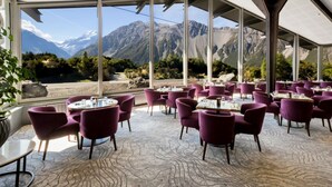 Un restaurante con vistas a la montaña, con sillas moradas y mesas redondas.