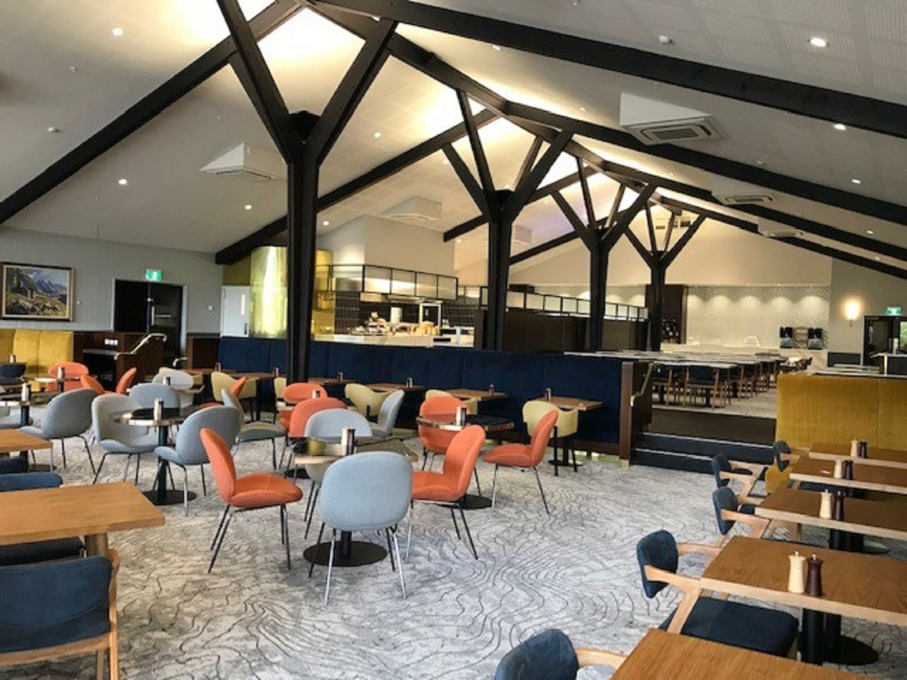 A spacious restaurant with high ceilings and exposed beams, featuring a mix of seating styles including tables and booths.