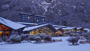 Un hotel moderno con varias construcciones, grandes ventanales y paisajes nevados.