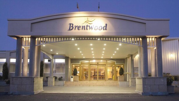Entrada de hotel con fachada curva, grandes puertas de vidrio y un letrero que dice "Brentwood".