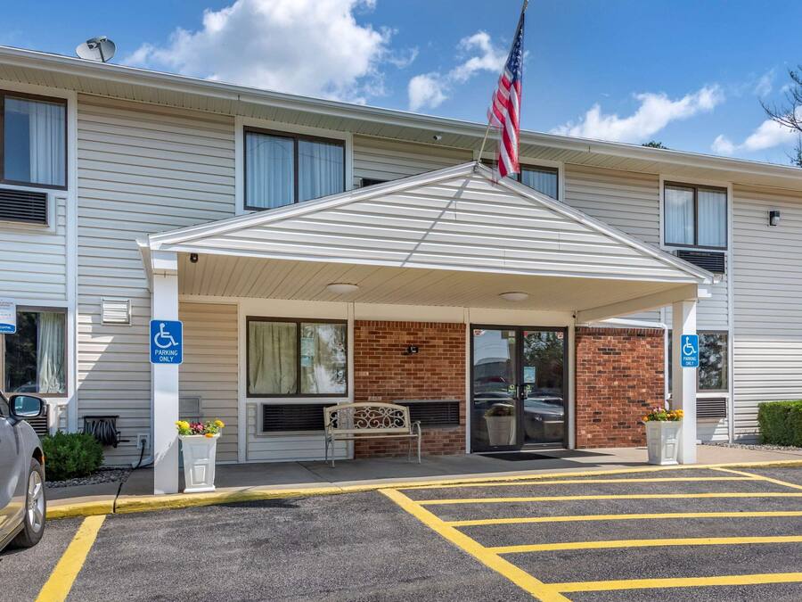 A hotel entrance with a covered waiting area, handicap accessible parking, and a flag.