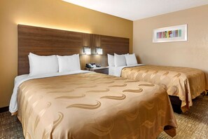 Habitación de hotel con dos camas, cabecero de madera, lámparas de noche y una obra de arte enmarcada en la pared.