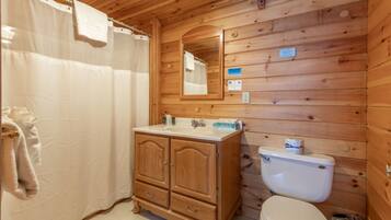 Een houten badkamer met een houten wastafel, toilet en douchegordijn.