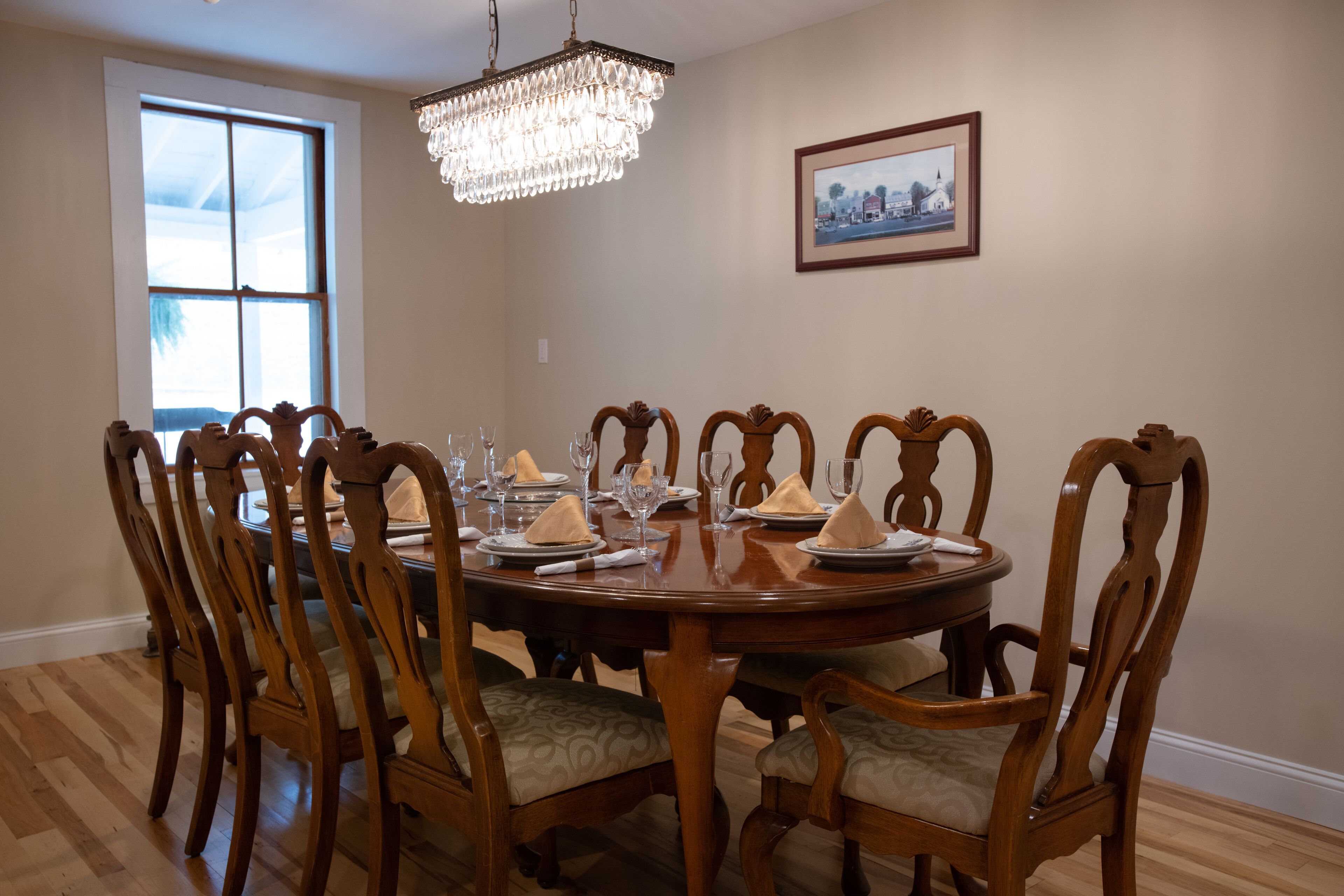 Comedor con una mesa redonda de madera dispuesta para seis personas, rodeada de sillas tapizadas con tela estampada.