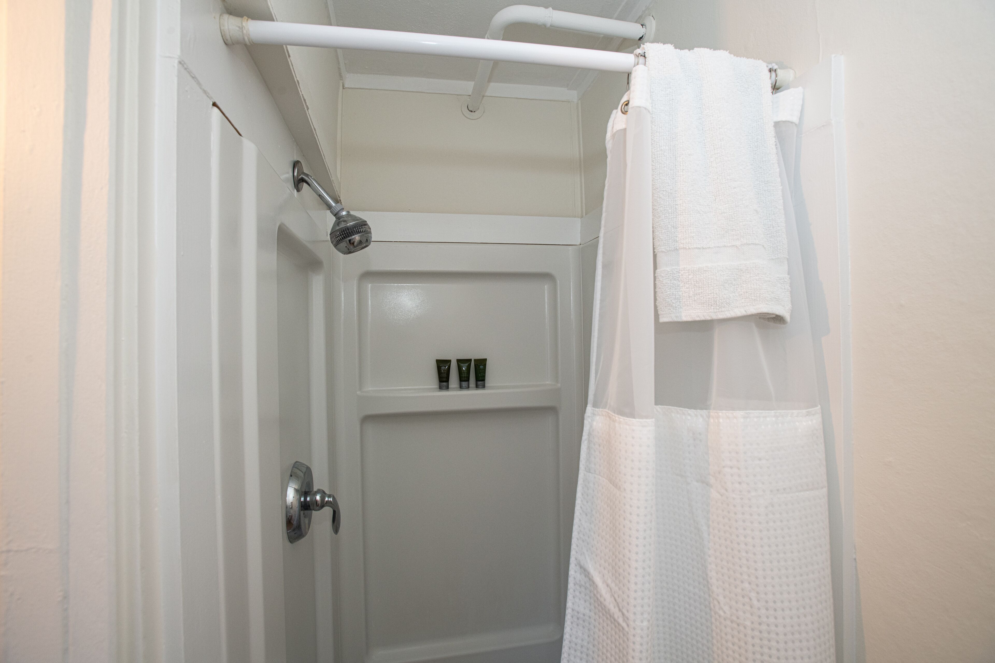 A bathroom with a shower, a towel rack, and a door with a handle.